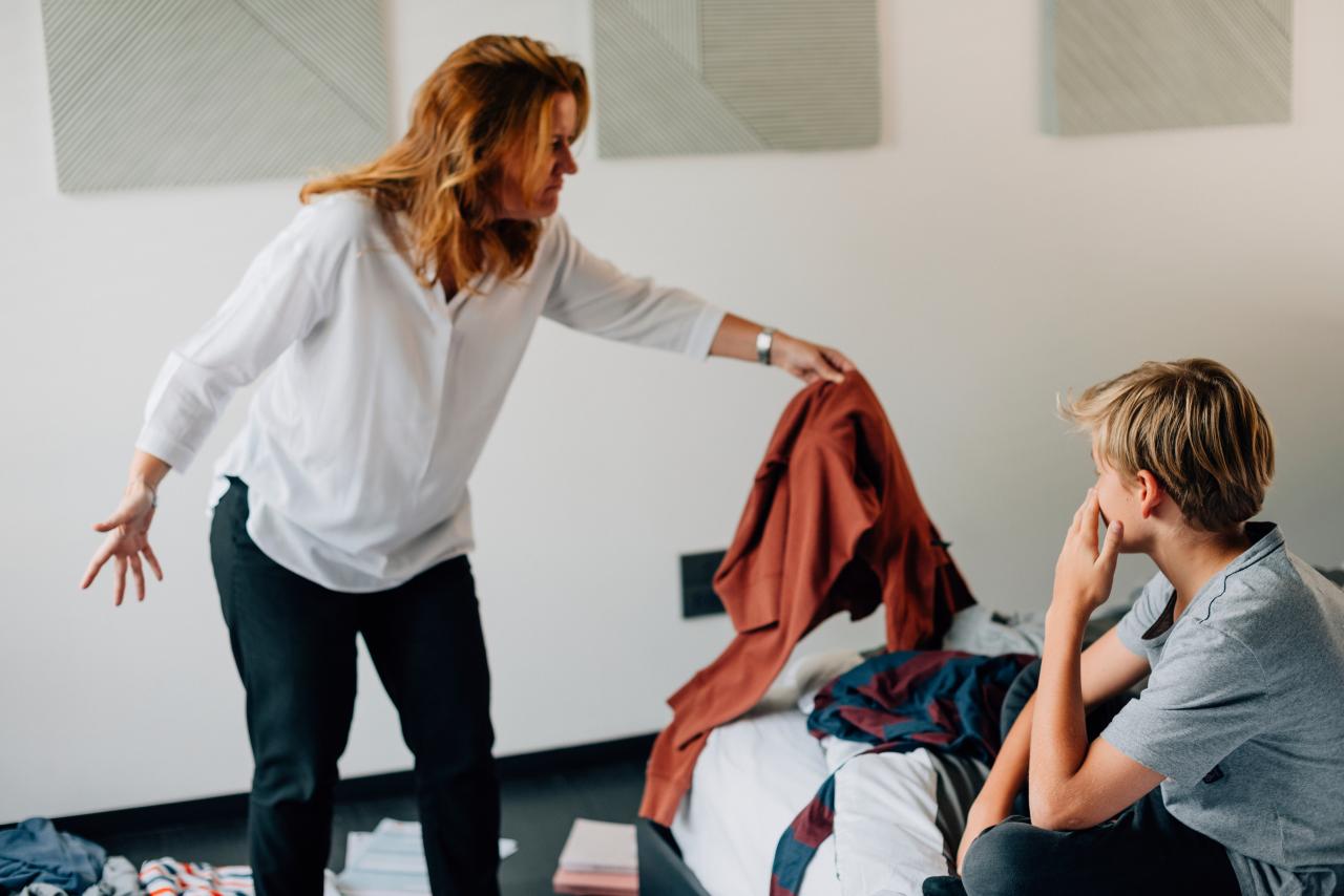 A woman holding a piece of clothing and gesturing to a boy | Source: Shutterstock